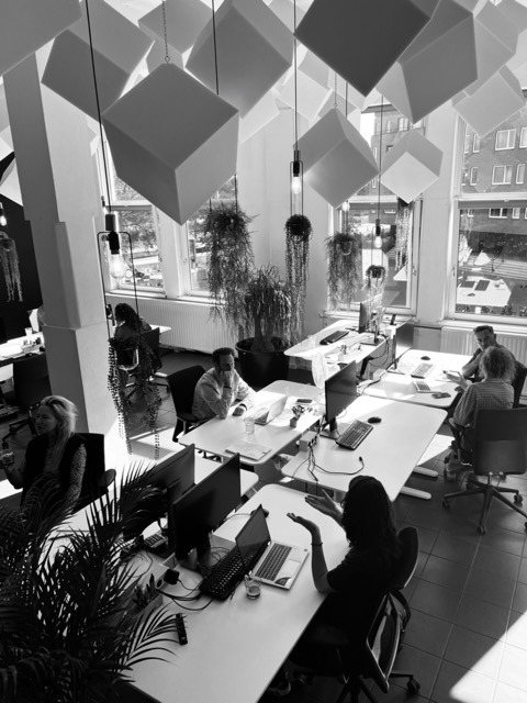 Zwart wit foto van het kantoor van mind work productions in amsterdam. er zitten mensen achter een bureau te werken