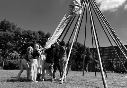 zwart wit foto van en team dat een grote tipi tent probeert op te zetten