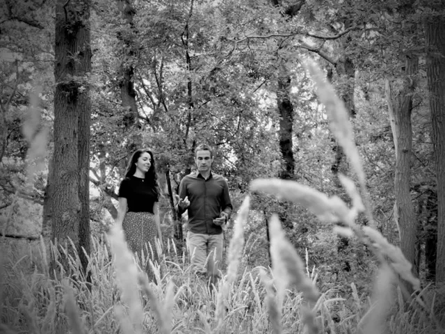 zwart wit fotovan twee mensen, een man en een vrouw, die in het bos lopen. het lijkt op een persoonlijke coaching.